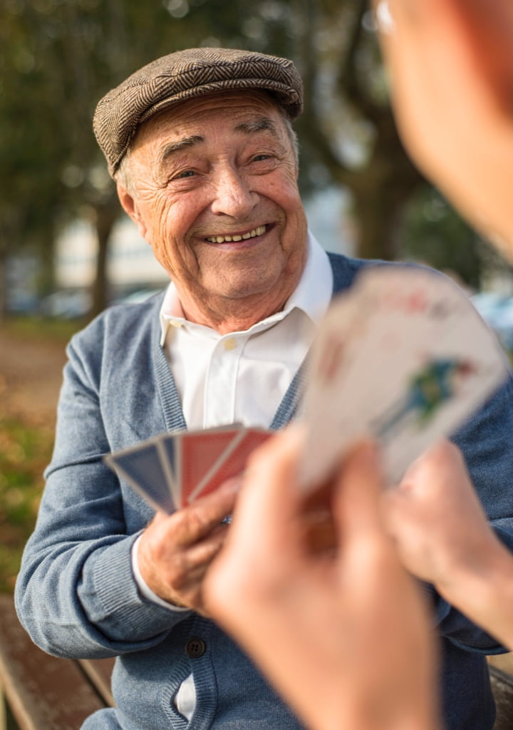 Elder gentleman wearing a cap playing cards